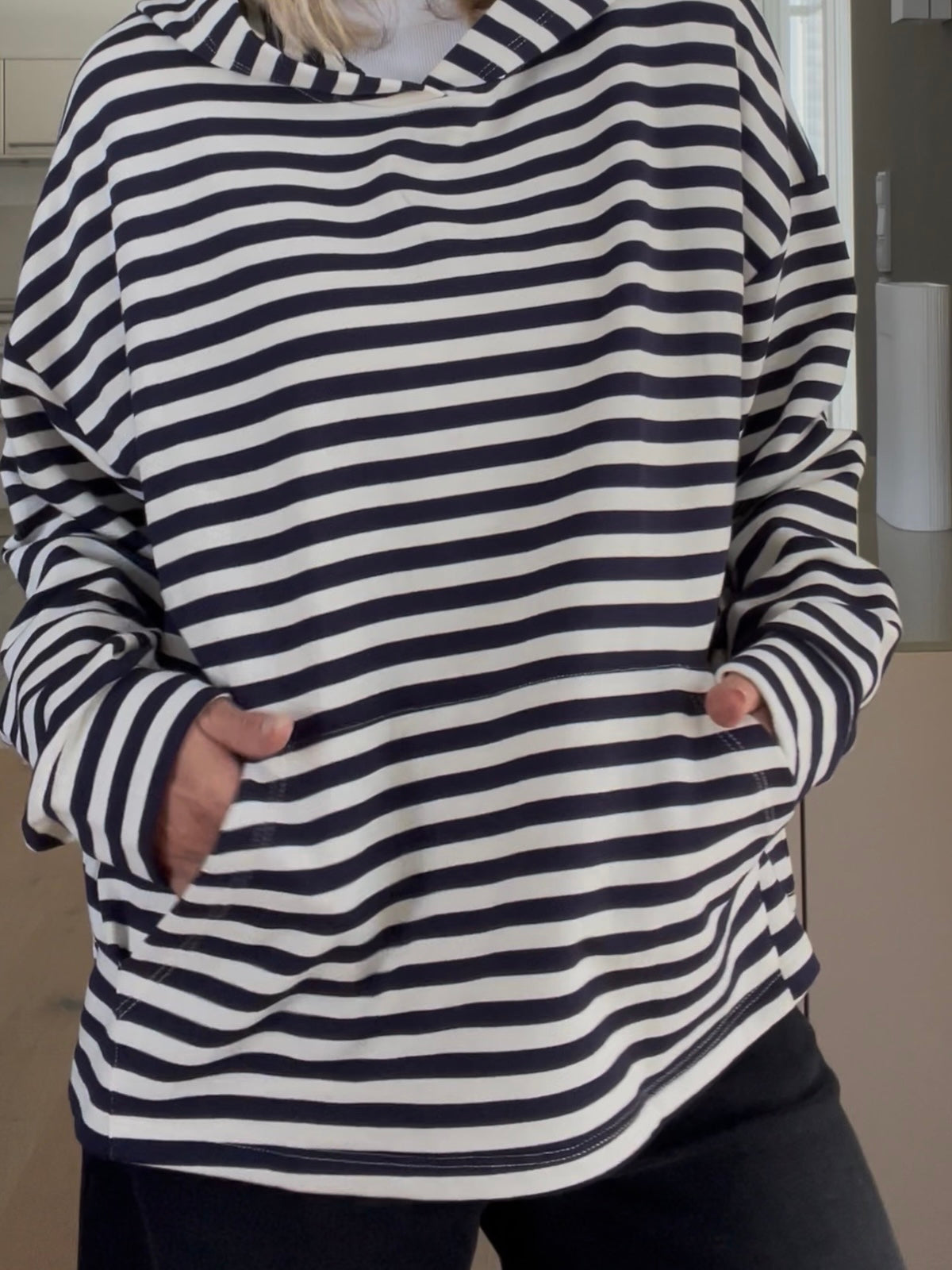 Nahaufnahme des Hoodies Thea in Blau-Creme, welche die prägnante Formsprache, das Streifenmuster und die aufgesetzte Kängurutasche im sportlich-eleganten Look zeigt.