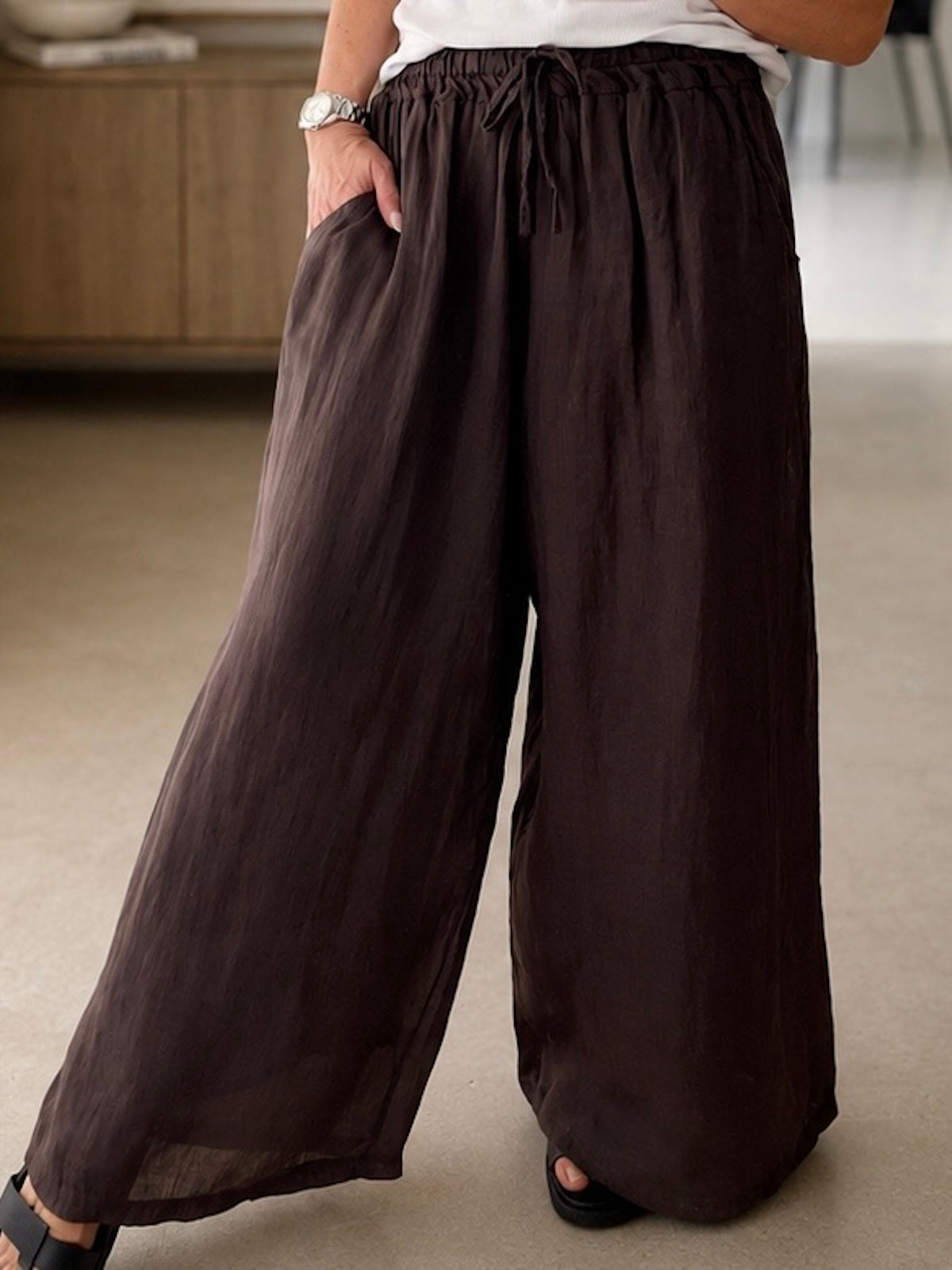 Nahaufnahme der dunkelbraunen Leinenhose Ariella mit Fokus auf den formstabilen Elastikbund, das Bindeband und die hochwertig integrierten, seitlichen Eingrifftaschen.