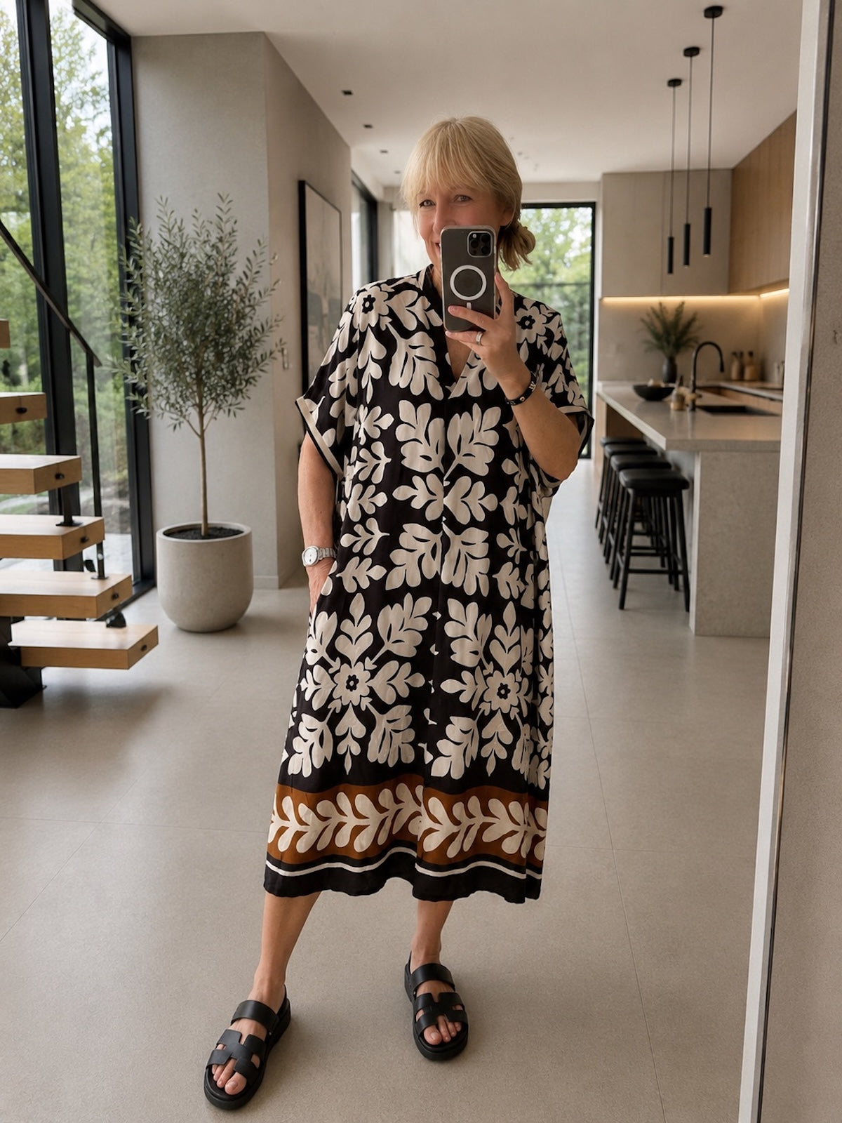 Vorderansicht des eleganten Viskose-Seidenkleids Lydia in Schwarz-Floral mit femininem V-Ausschnitt, langen Ärmeln und stufig fließendem Maxirock in einem hellen Studio.