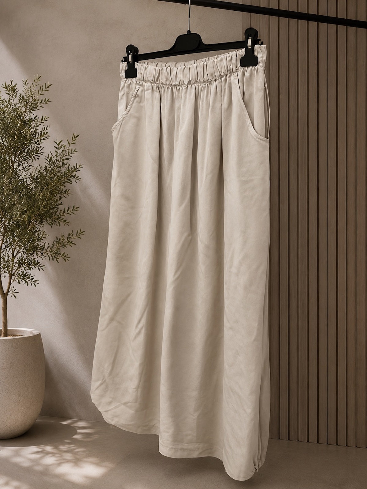 Clean freigestellter Damen Maxirock Clara im hellen Farbton Stone (Sand-Beige) mit gerafftem Gummibund und praktischen seitlichen Eingriffstaschen, hängend vor neutralem Hintergrund