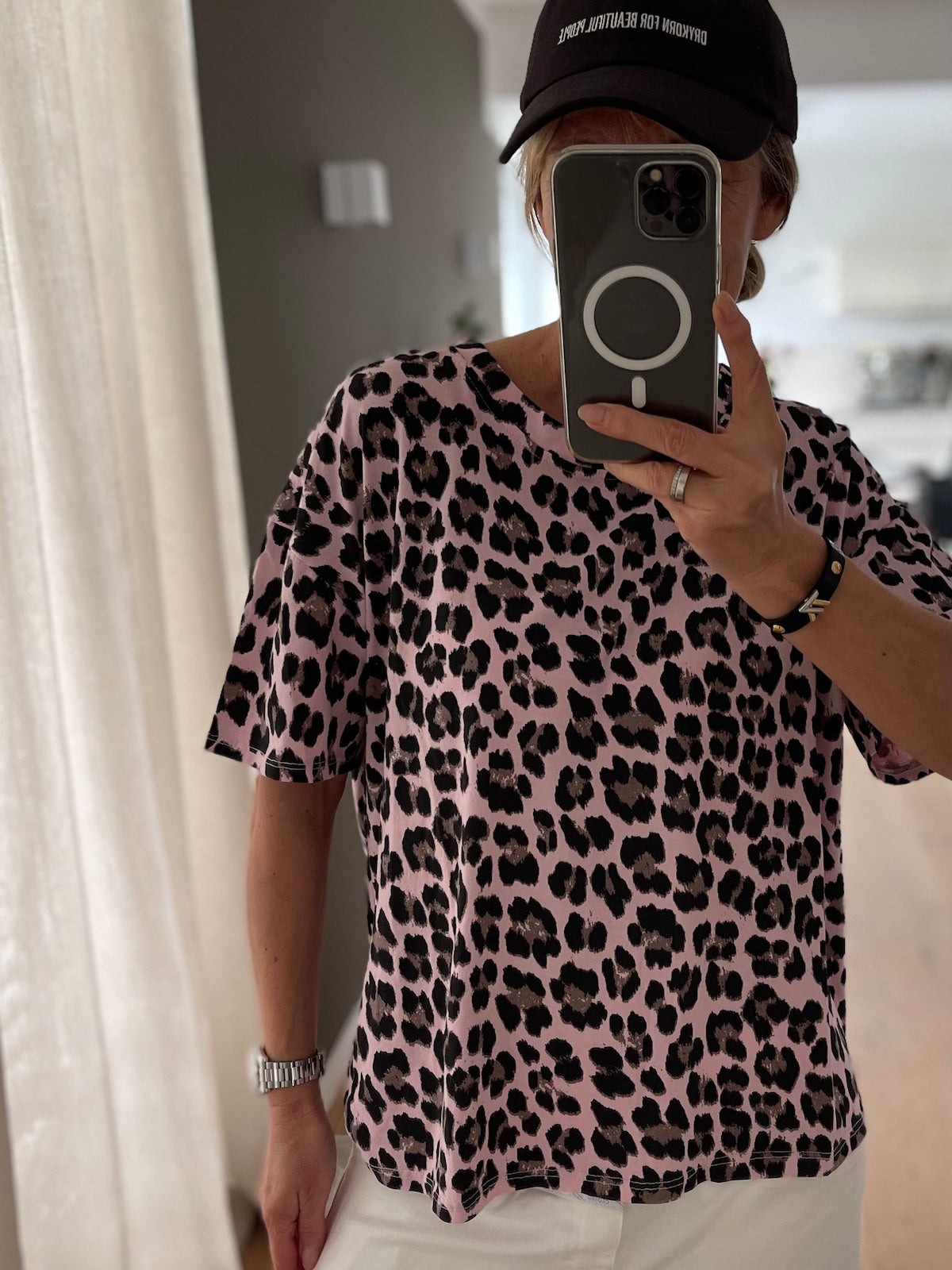 Front Nahaufnahme des roséfarbenen T-Shirts Bea mit schwarzem Leo-Muster, zu weißer Hose, Fokus auf Print und Schnitt.
