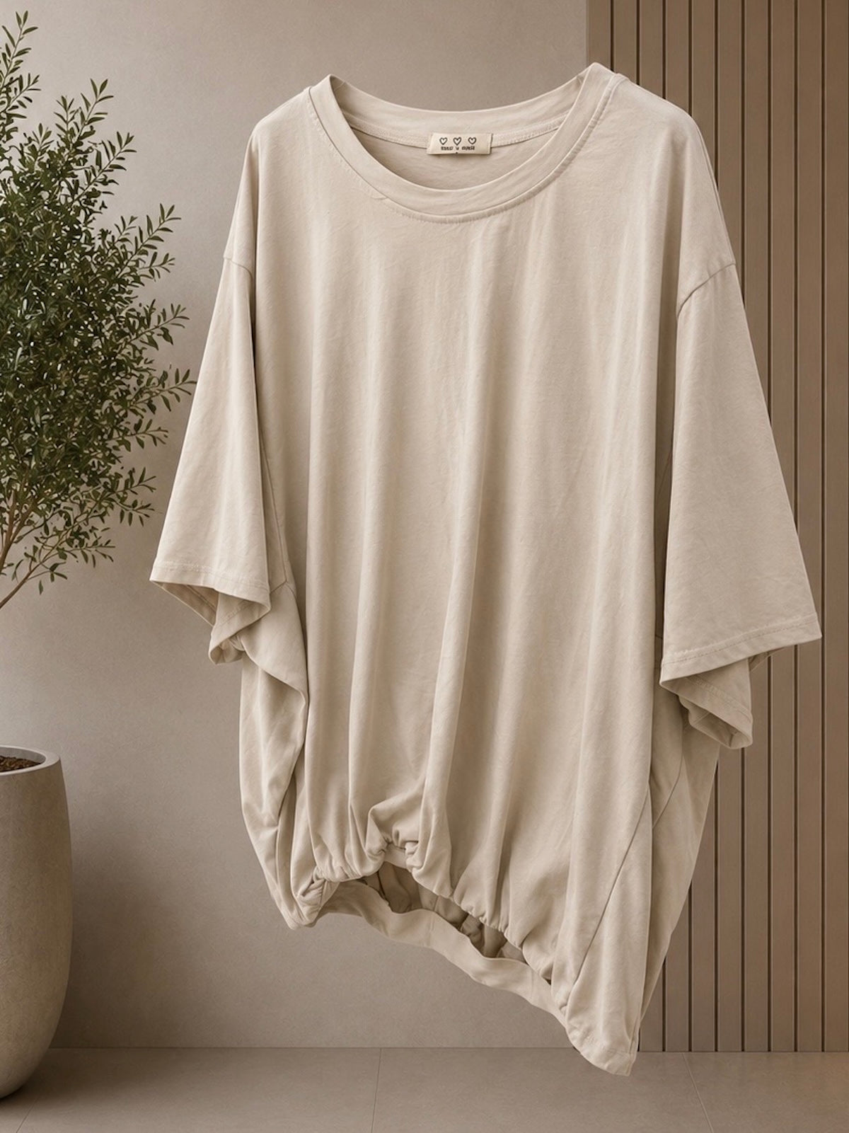 Clean freigestelltes Damen T-Shirt Emily in Stone (helles Sand-Beige) im modernen Cropped-Schnitt mit charakteristischem Fledermaus-Ärmelansatz und gerafftem Saumbund vor neutralem Hintergrund