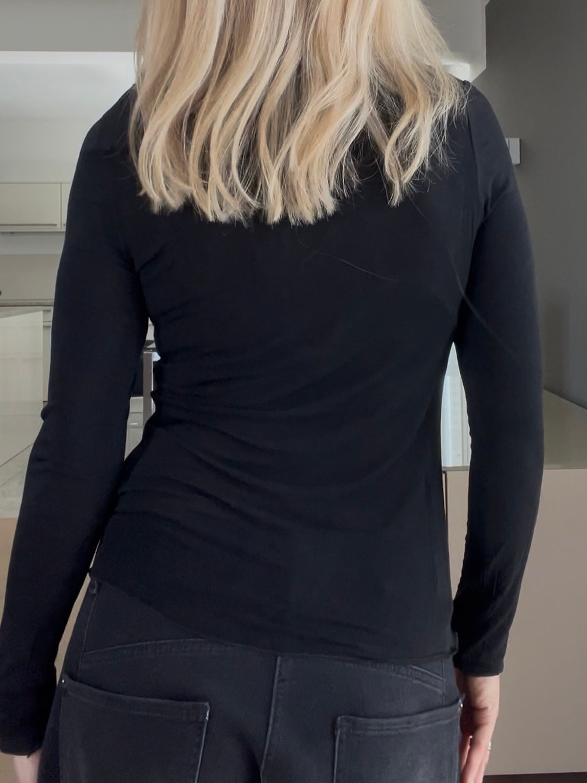 Rückansicht des feinen Shirts Luna in Schwarz, die den formstabilen, körpernahen Sitz und die scharf gezeichnete Silhouette des Cashmere-Mix-Materials zeigt.