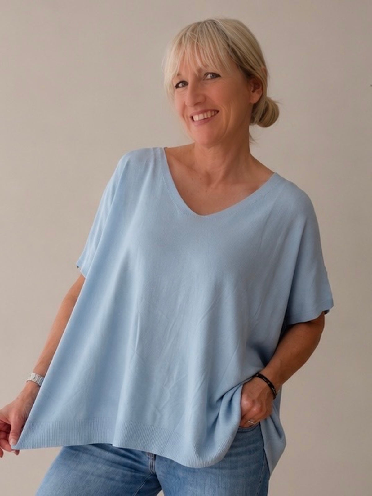 Blondes Modell (1,68 m) trägt im Spiegel-Selfie das weit fallende, hellblaue V-Neck Shirt Maria. Der fließende, kühle Viskose-Stoff umspielt locker die Figur, sportlich kombiniert mit einer lockeren, hellen Blue Jeans.