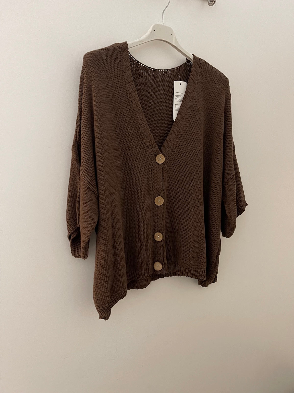 Der braune Strick Cardigan Daisy aus Baumwoll-Mix hängt auf einem weißen Kleiderbügel und zeigt die Knopfleiste sowie die gerippten Bündchen. SILKE MODEN Kitzingen.