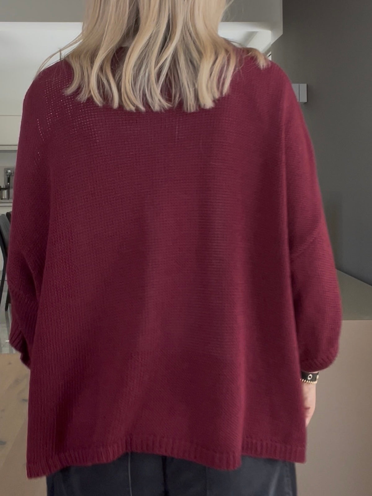 Rückansicht des Strickcardigans Daisy in Burgundi, die das strukturierte Volumen, das kompakte Maschenbild und den sauberen Rippstrick-Abschluss am Saum zeigt.