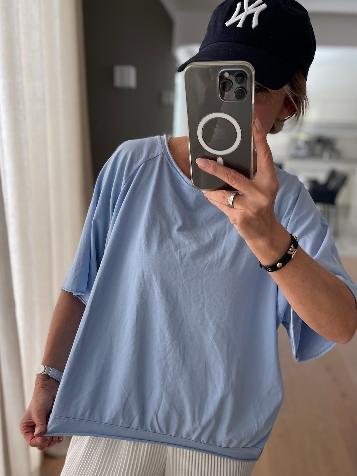 Spiegel-Selfie eines Modells im hellblauen T-Shirt Mary, kombiniert mit einer dunklen Kappe. Der lockere Fall der Baumwolle und die sportliche Schnittführung durch die Raglanärmel werden optimal präsentiert.