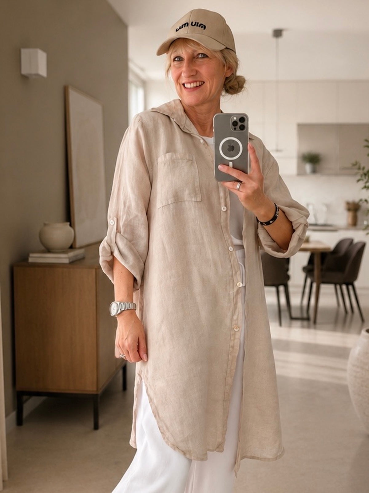 Halboffenes Damen Leinen-Blusenkleid Bonny in Sand-Beige bzw. Stone, getragen über einer fließenden weißen Sommerhose, Fokus auf den geschwungenen Saumverlauf mit Beinschlitzen