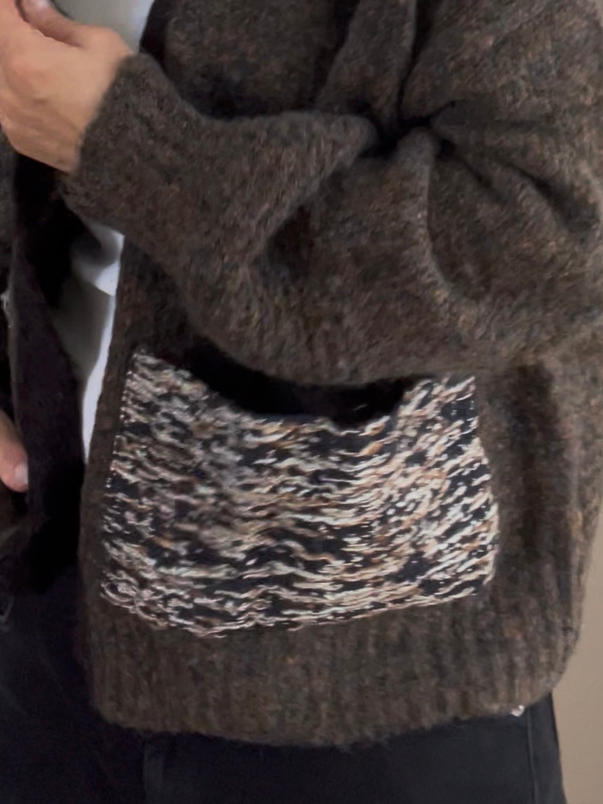 Nahaufnahme der texturierten, mehrfarbigen aufgesetzten Tasche des braunen Cardigans Fia, die das kompakte Maschenbild und die hochwertige Materialstruktur zeigt.