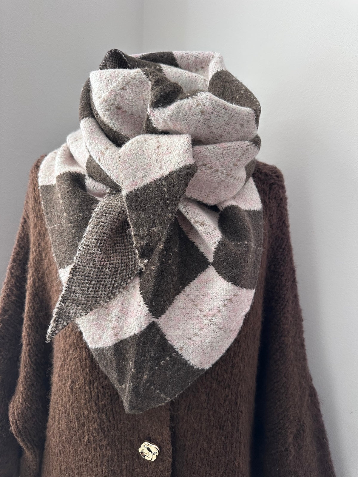 Exklusiver Dreieck-Schal Burlie in Braun und Rosé mit markantem Karo-Muster, formstabil und strukturiert drapiert auf einer Schaufensterpuppe über einem braunen Strickteil.