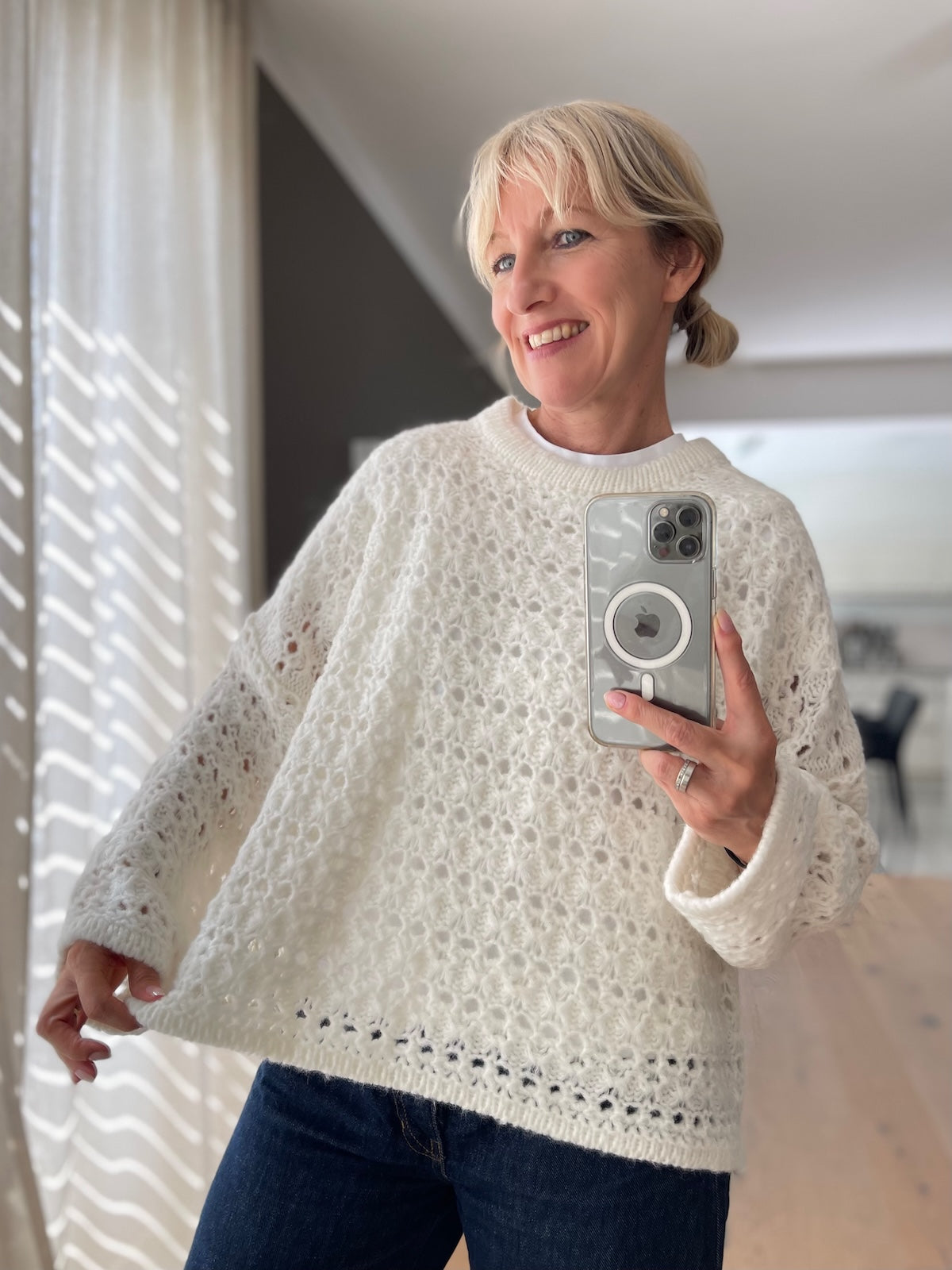 Sportlich eleganter Grobstrick Pullover Nomi in Wollweiß im modernen Boxy-Schnitt mit markanter Ajour-Struktur, kombiniert mit einer dunklen Jeans.