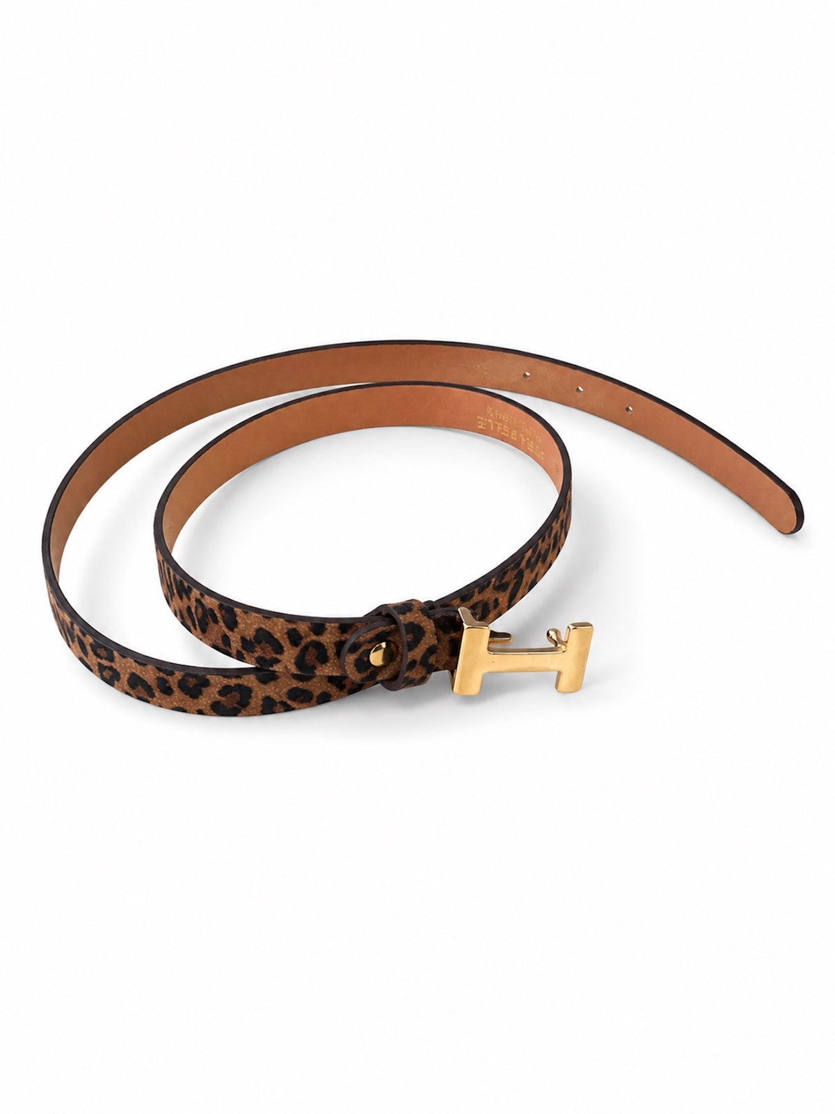 Zusammengerollter, 2 cm schmaler Damen-Ledergürtel Modell Hermi im klassischen Leoparden-Muster. Im Vordergrund ist die auffällige, goldfarbene Metallschließe im H-Design sichtbar, präsentiert vor einem weißen Hintergrund.