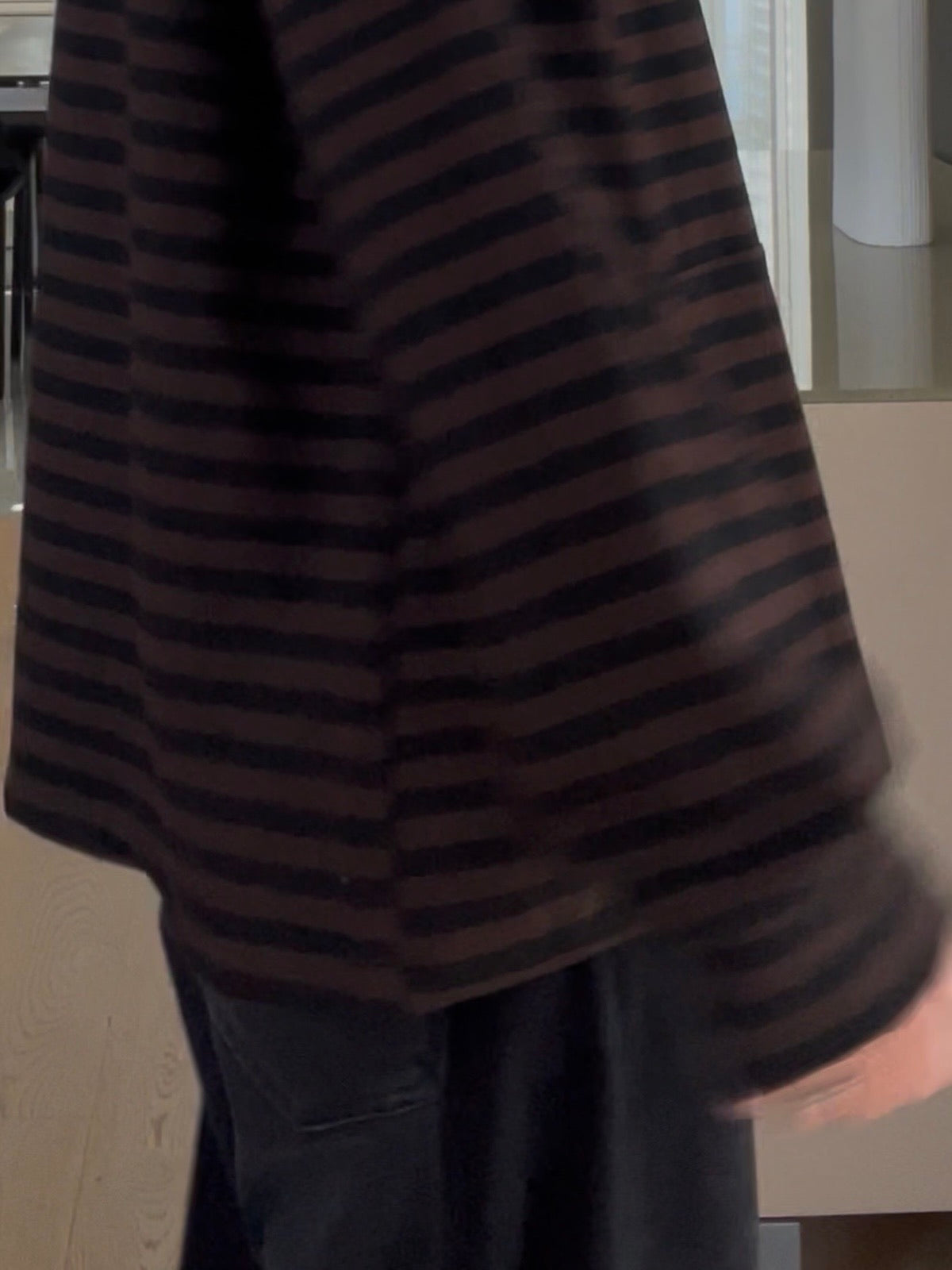 Nahaufnahme des Hoodies Thea in Schoko-Schwarz, welche die prägnante Formsprache, das dunkle Streifenmuster und die aufgesetzte Kängurutasche im sportlich-eleganten Look zeigt.