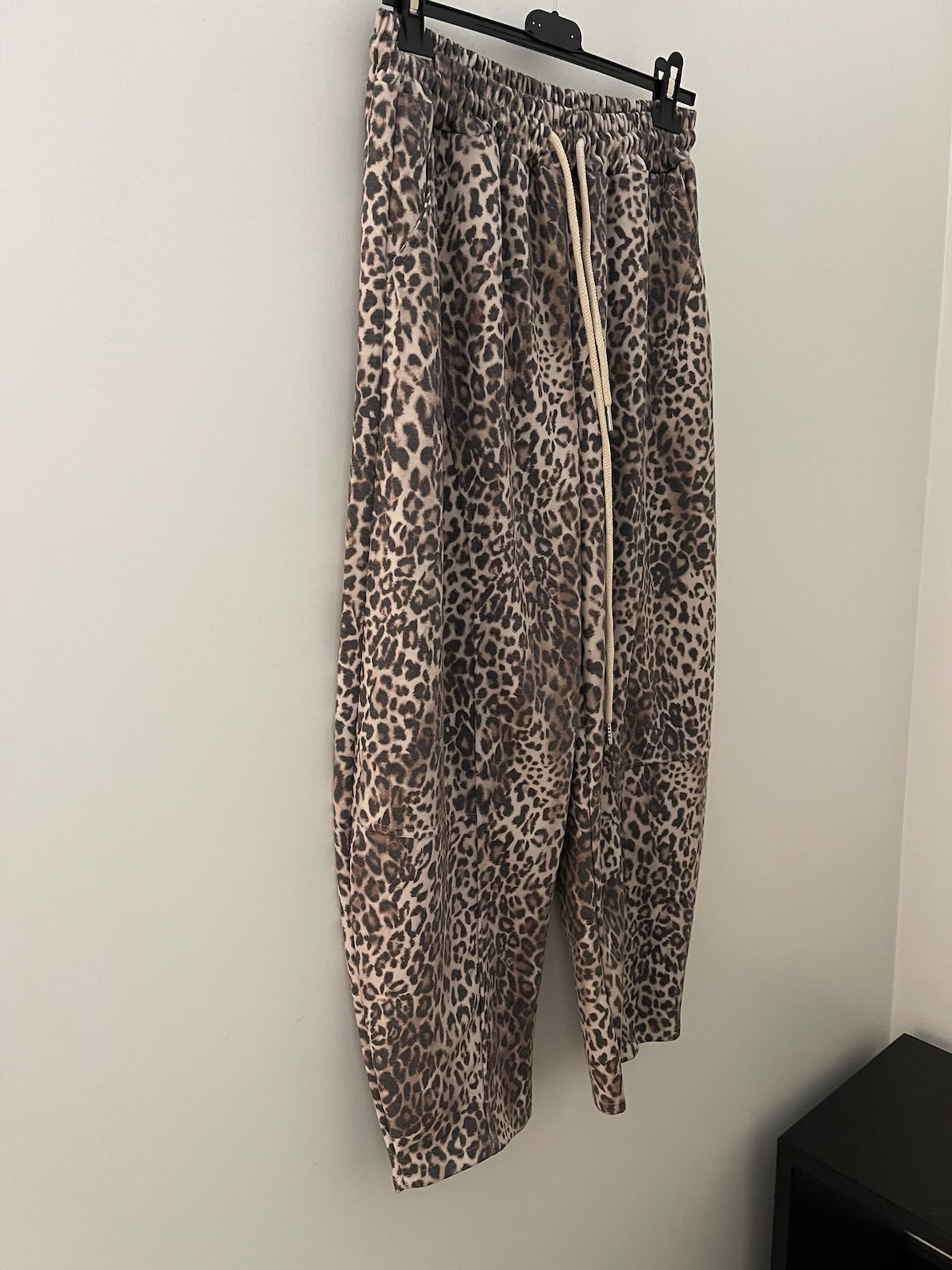 Die Hose Brooke mit markantem Leopardenmuster hängt an einem schwarzen Kleiderbügel und zeigt den modernen Schnitt sowie den Kordelzug. SILKE MODEN Kitzingen.