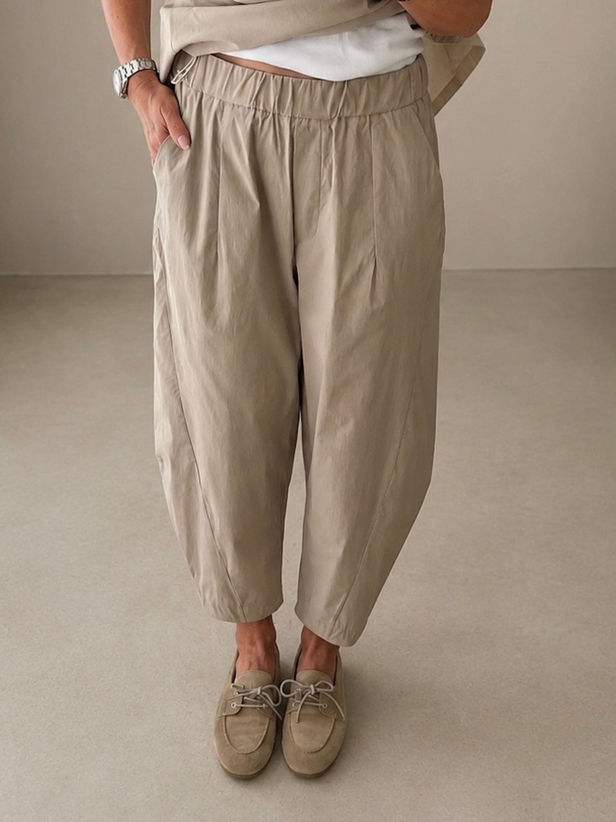 Nahaufnahme der beigen Hose Elisa in Stone von vorne zur präzisen Abbildung der dezenten Bundfalten, der seitlichen Eingrifftaschen und der modern definierten Beinsilhouette.