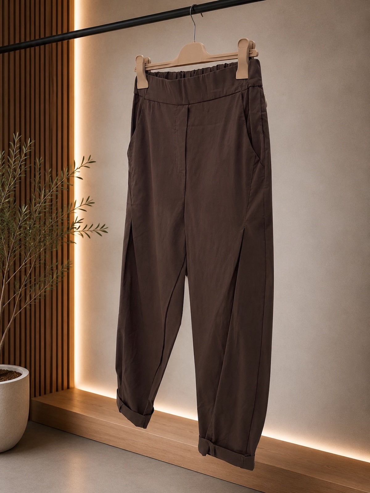 Detailaufnahme der braunen Bundfaltenhose Larissa mit Fokus auf die glatte Frontpartie, den elastischen Bund und die seitlichen Eingrifftaschen.