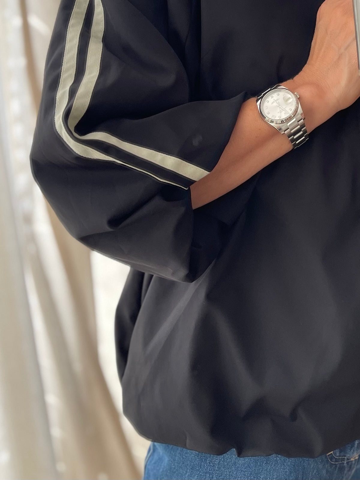 Detailansicht der Jacke Adi in Schwarz mit Fokus auf die sportlichen Kontraststreifen der 3/4-Ärmel und das hochwertige, strukturierte Material.