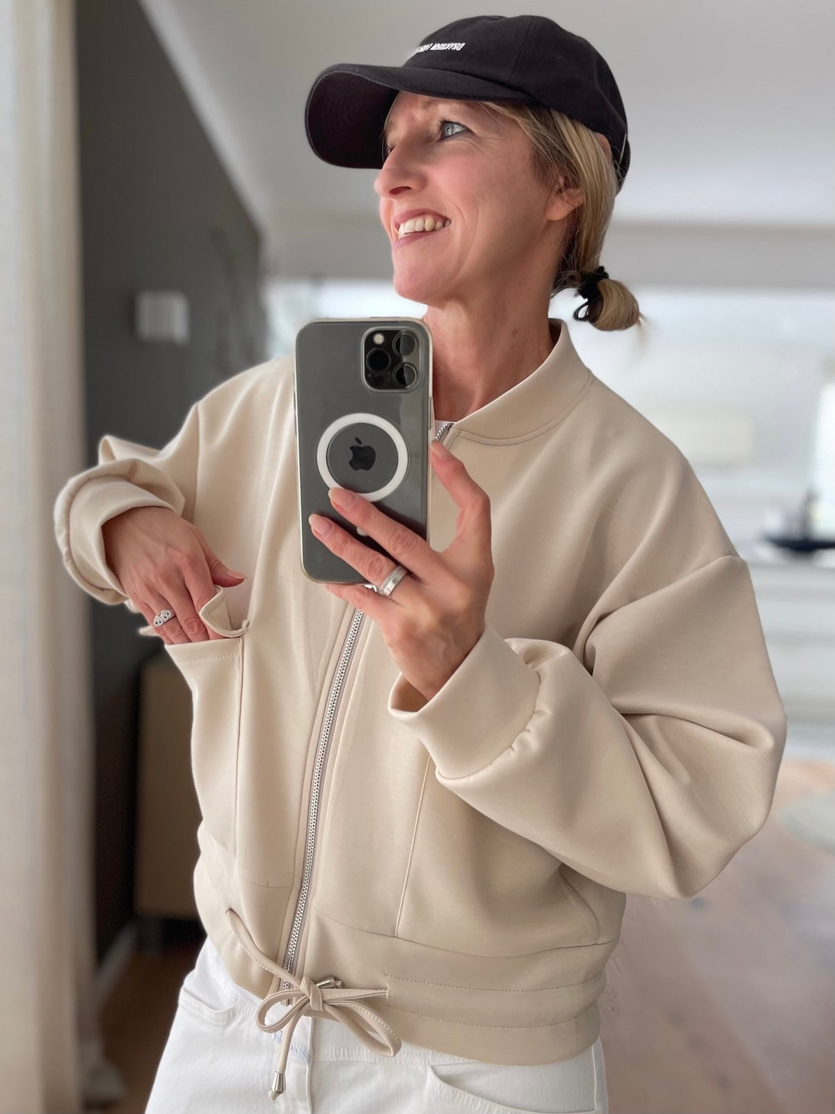 Sportliche Damen Jacke Franzi in Creme mit Reißverschluss und Kordelzug am Saum kombiniert mit weißer Hose und Cap