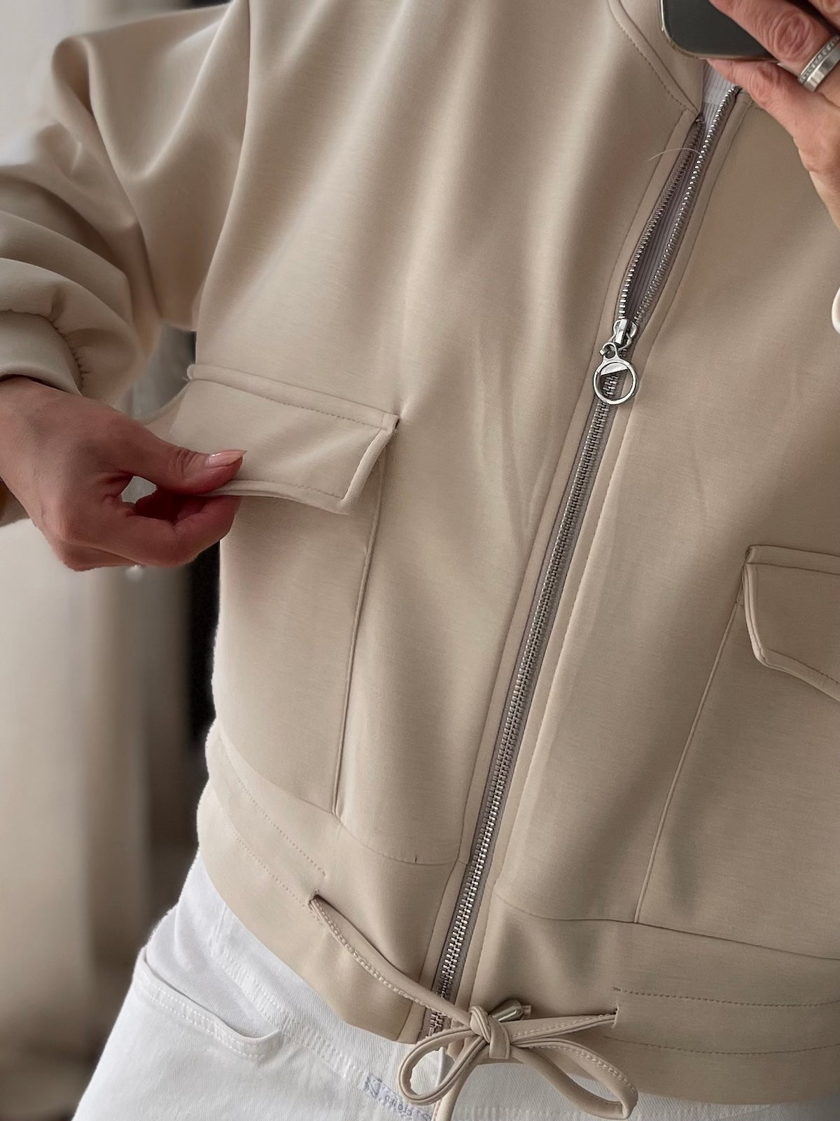 Sportliche Damen Jacke Franzi in Creme mit Reißverschluss und Kordelzug am Saum kombiniert mit weißer Hose und Cap