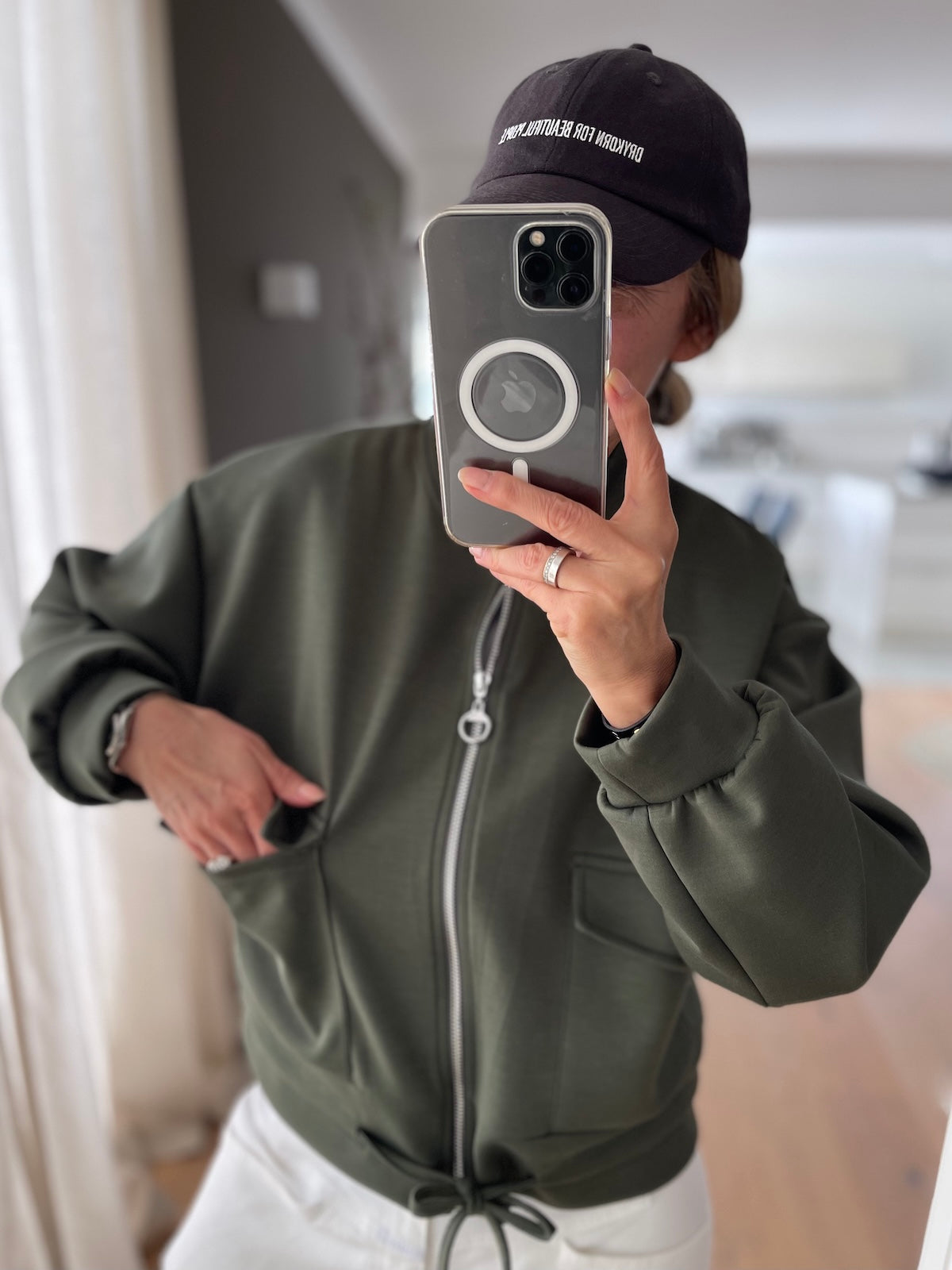 Sportliche Damen Jacke Franzi in Grün mit Reißverschluss und Kordelzug am Saum kombiniert mit weißer Hose und Cap