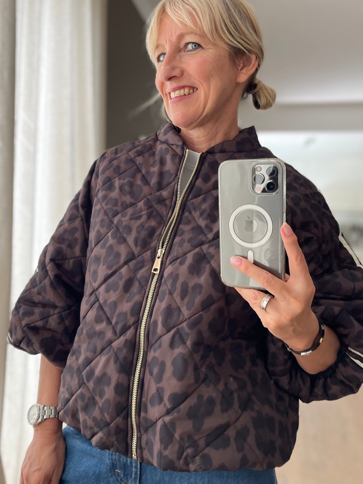 Sportlich elegante Blouson-Jacke Hannah in Leo Braun in markanter Stepp-Optik mit goldfarbenem Reißverschluss und sportlichen Ärmelstreifen, kombiniert mit einer blauen Jeans.