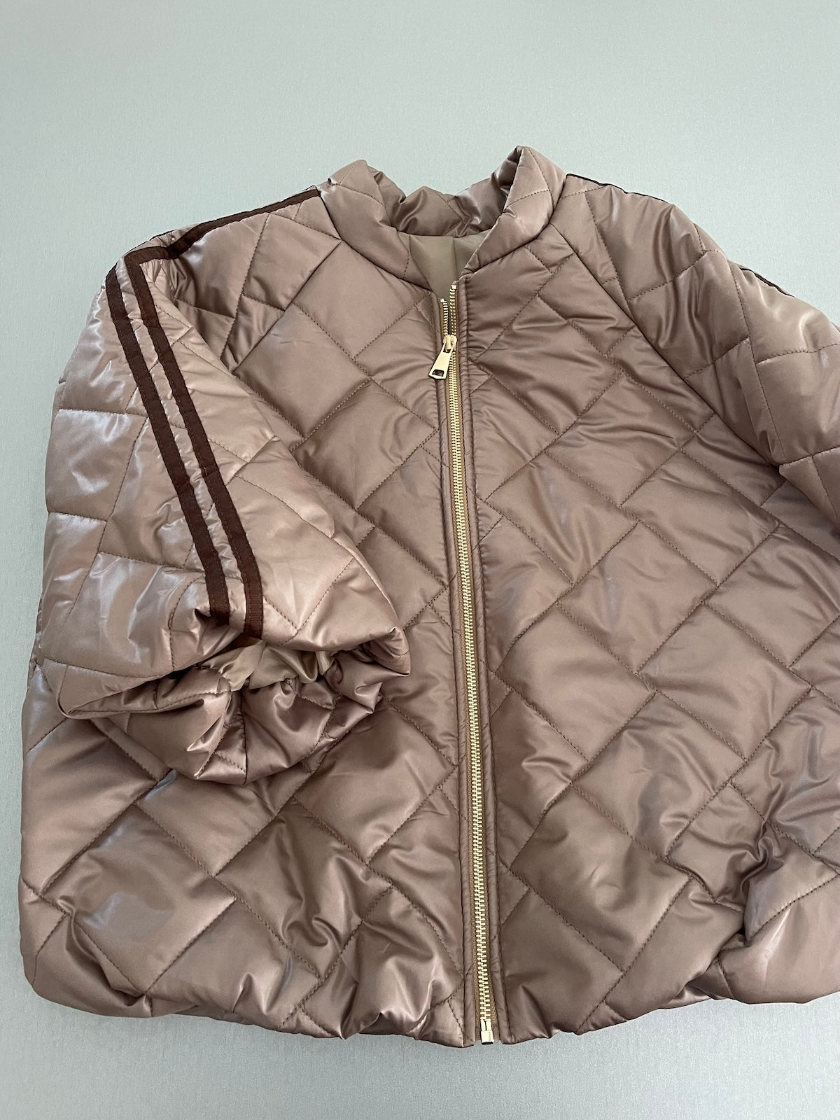 Frontansicht der kompakten Stepp-Jacke Hannah in Taupe, die durch den formstabilen Elastikbund am Saum eine klare Silhouette definiert.