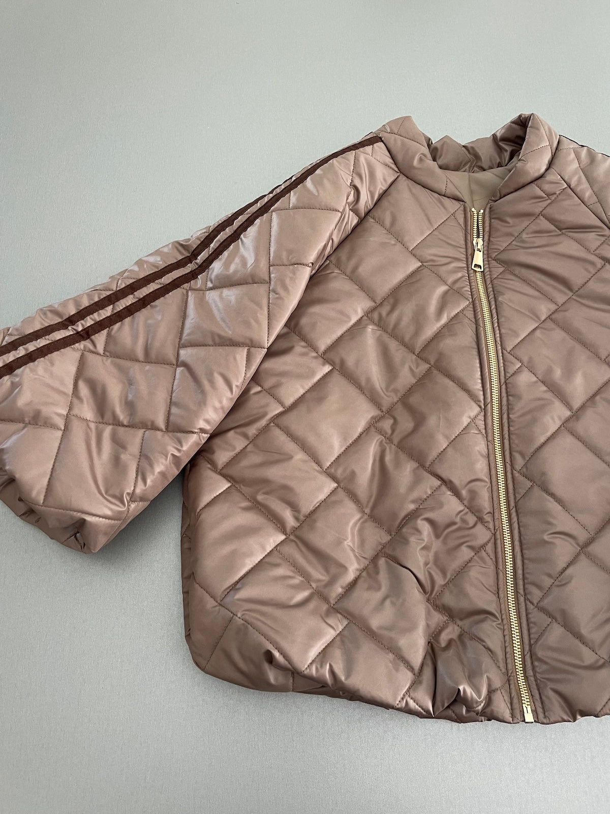 Detailansicht der Jacke Hannah in Taupe mit Fokus auf die sportlichen braunen Kontraststreifen an den 3/4-Ärmeln und die hochwertige Stepp-Struktur.