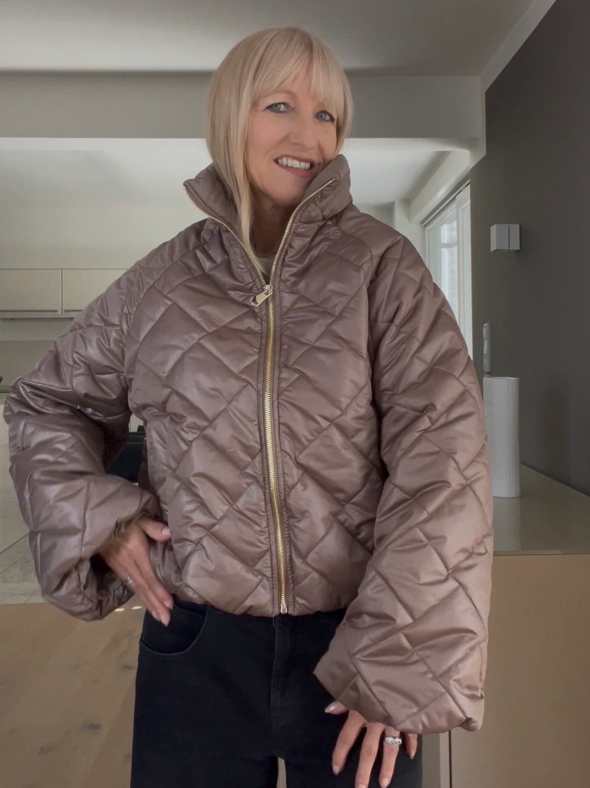 Nahaufnahme der Jacke Jany in Taupe, welche den markanten Stehkragen, die prägnante Formsprache und den hochwertigen, goldfarbenen Reißverschluss im sportlich-eleganten Look zeigt.