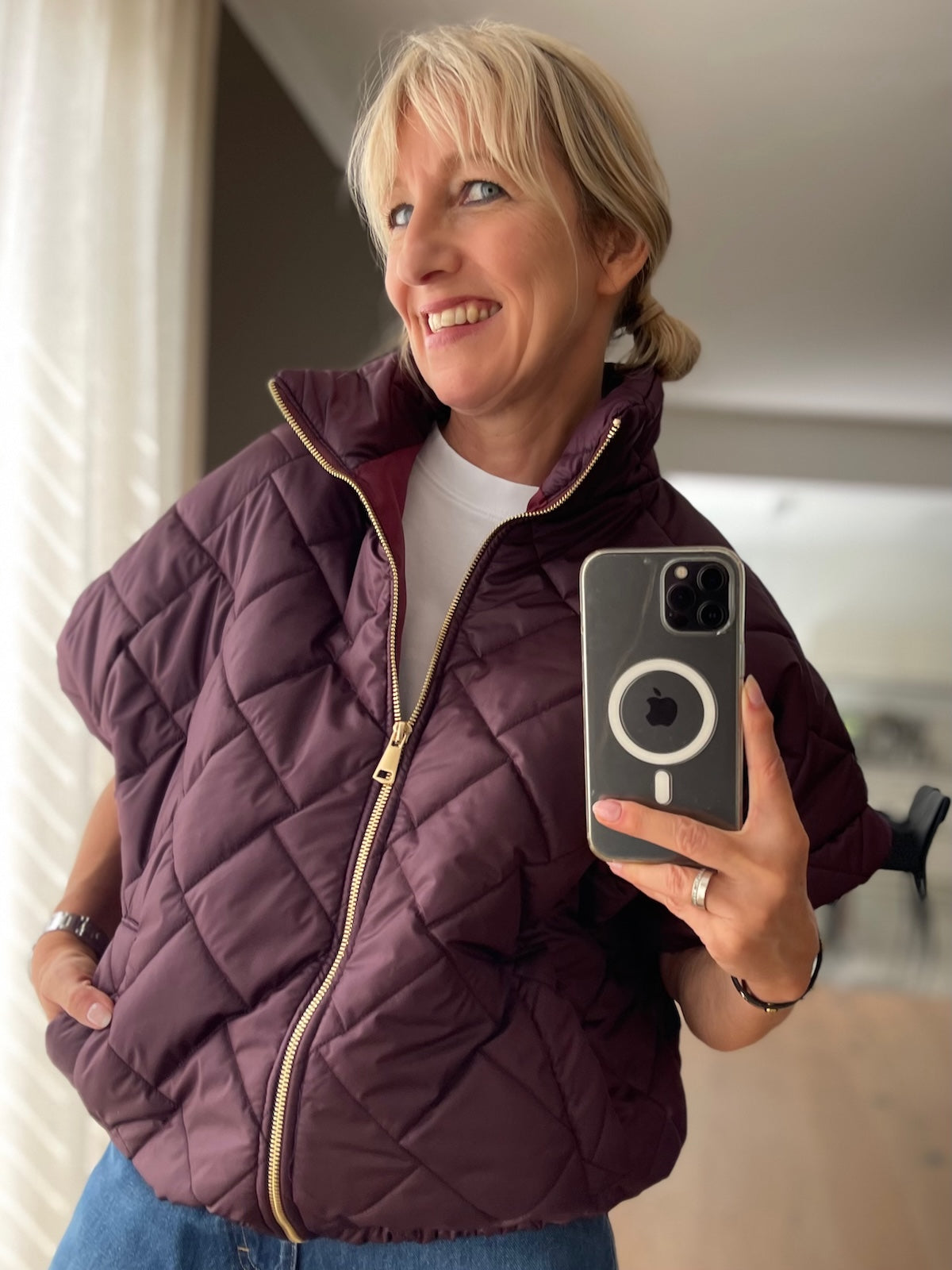 Dame trägt edle Kurzarm-Steppjacke Ruby in Mulberry im Layering-Look über einem weißen Langarmshirt.