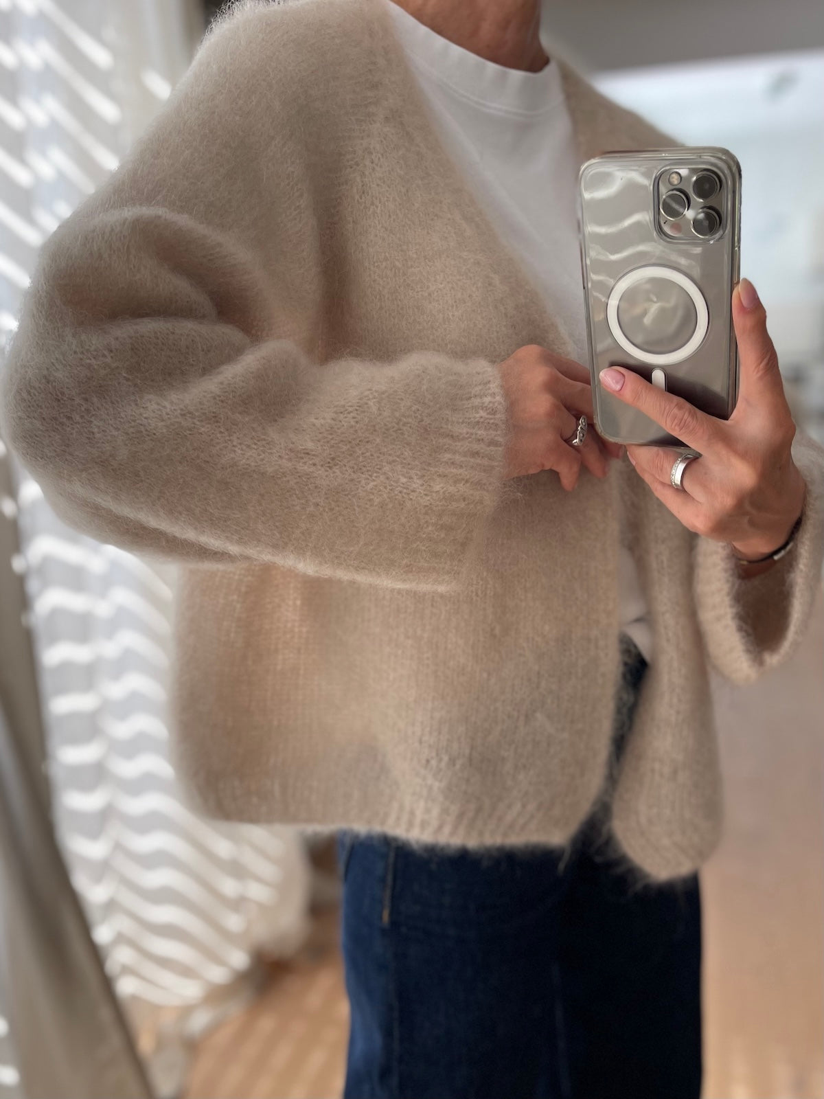 Detailansicht des weichen Mohair Cardigans Mila in Beige, getragen über einem weißen Shirt im Layering-Look.
