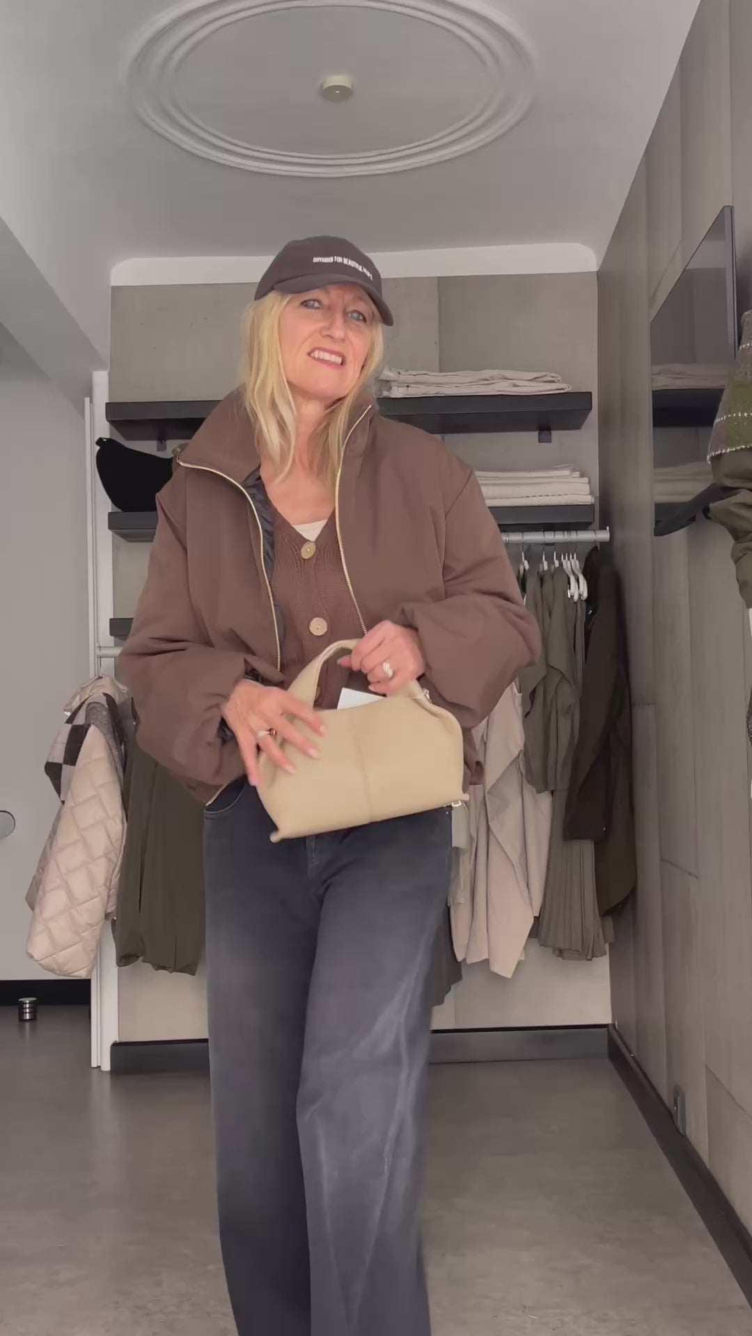 Frau präsentiert im Video die elegante Jacke Sofia in edlem Braun mit goldfarbenem Reißverschluss im modernen Boxy-Style.