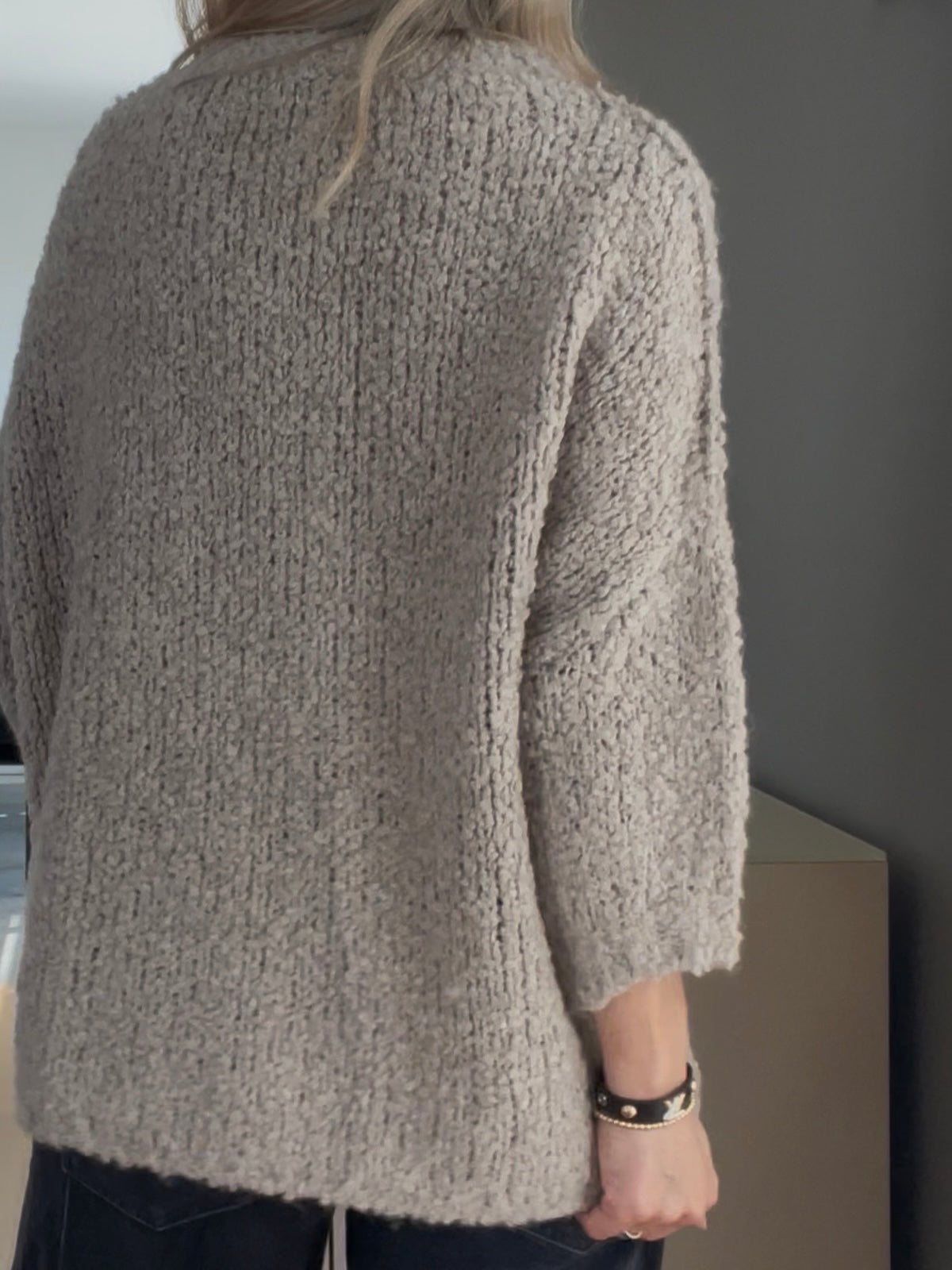 Detailaufnahme der Rückseite des Pullovers Jola in Greige, welche die überschnittenen Schultern und das strukturierte Volumen des weiten Ärmels hervorhebt.