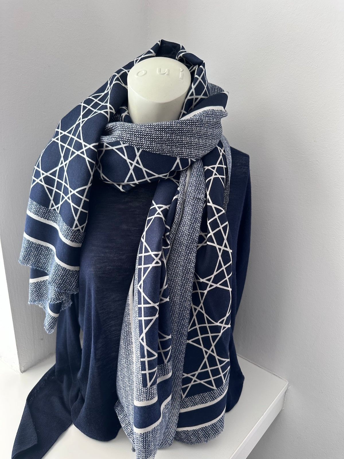 Großzügiger Schal Noa in Navy mit klar definierter Linienführung und Streifenbordüre, elegant kombiniert mit einem dunkelblauen Oberteil.