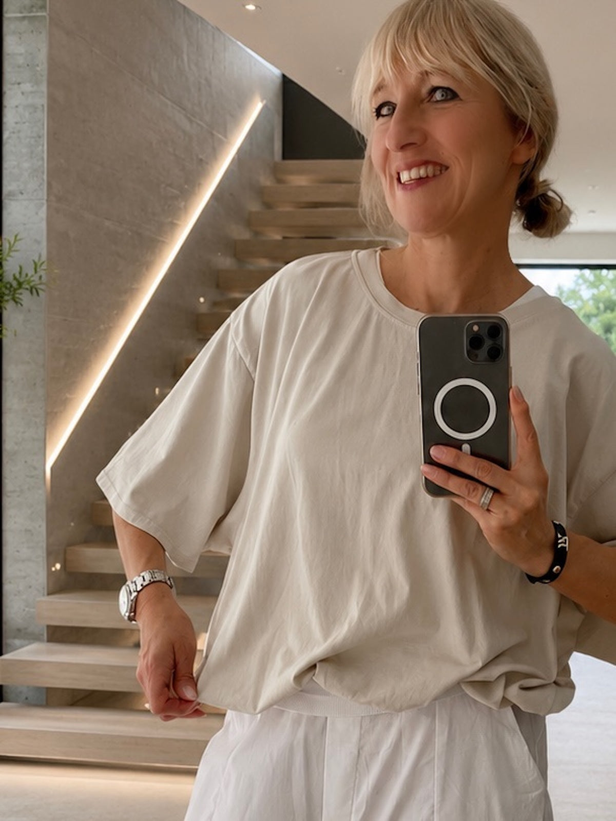 Exklusives Damen T-Shirt Emily in Stone im edlen Boxy-Style, getragen von blondem Modell, Fokus auf den formstabilen Elastikbund und den kurzen Sitz auf der Hüfte