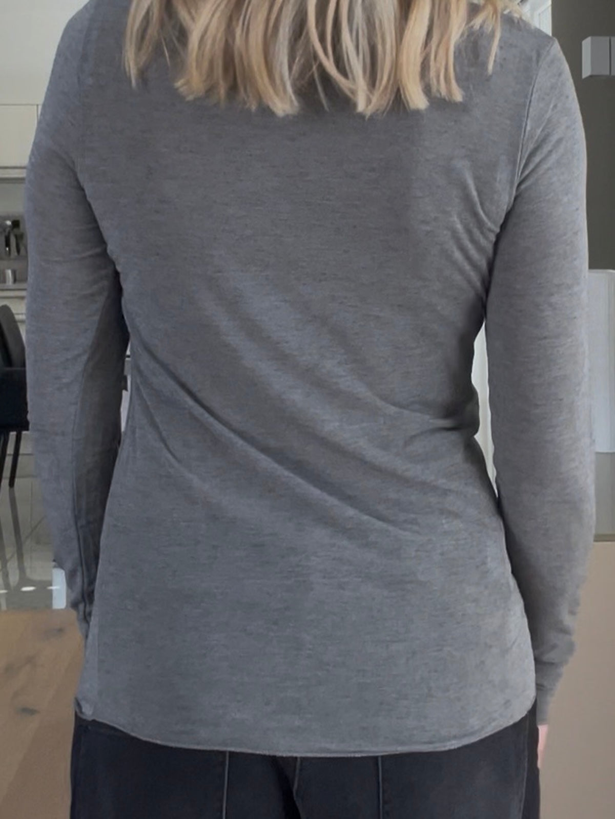 Rückansicht einer modebewussten Frau, edle Shirt Luna in Grau mit modernem U-Boot-Ausschnitt, perfekt gestylt als hochwertiges Basic unter einem Cardigan zur dunklen Denim.