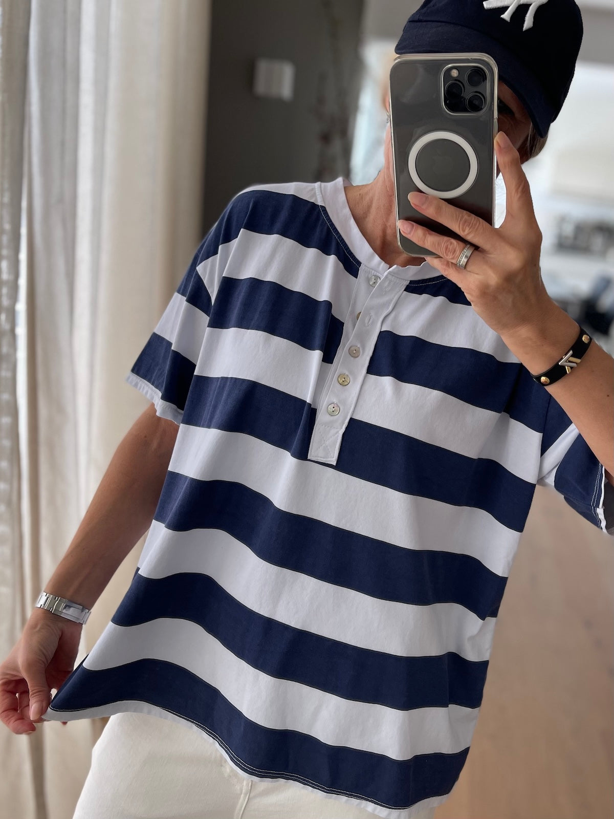 Lässiges Damen Streifenshirt Michelle in Blau Weiß mit halber Knopfleiste, sportlich kombiniert mit weißer Hose und dunkler Cap, front