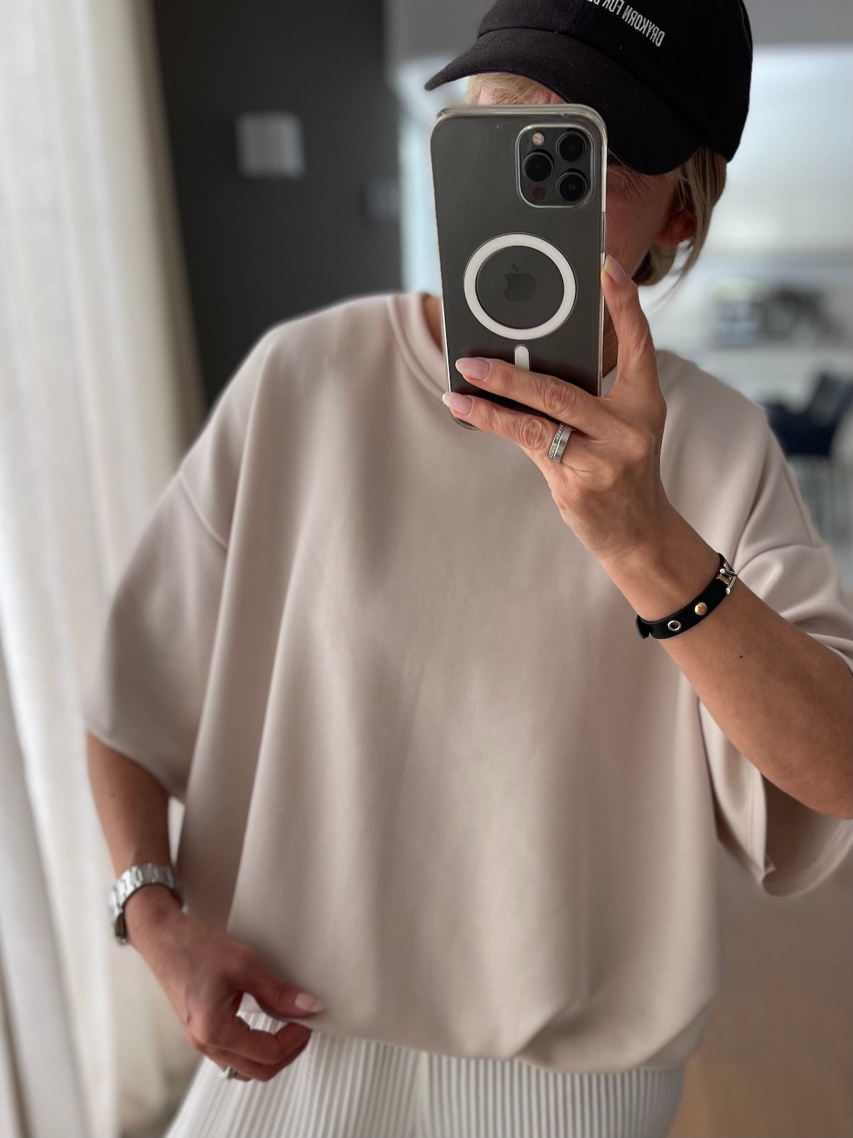 Spiegel-Selfie eines Modells mit Cap, das den fließenden, formstabilen Fall und das cleane Design des Oversized-Shirts Lilly in der Farbe Stone zeigt.