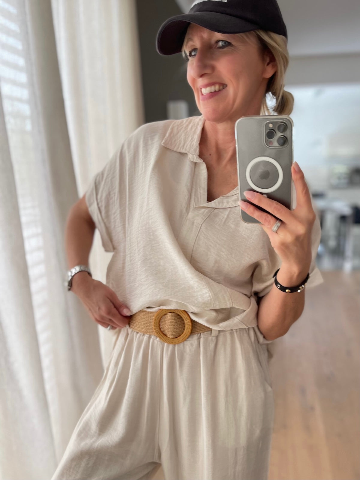 Sommerliches Outfit: Das hellbeige Shirt des Zweiteilers Chloe ist vorne in die weite Hose eingesteckt und wird mit einem breiten, geflochtenen Bastgürtel mit runder Schnalle tailliert getragen.